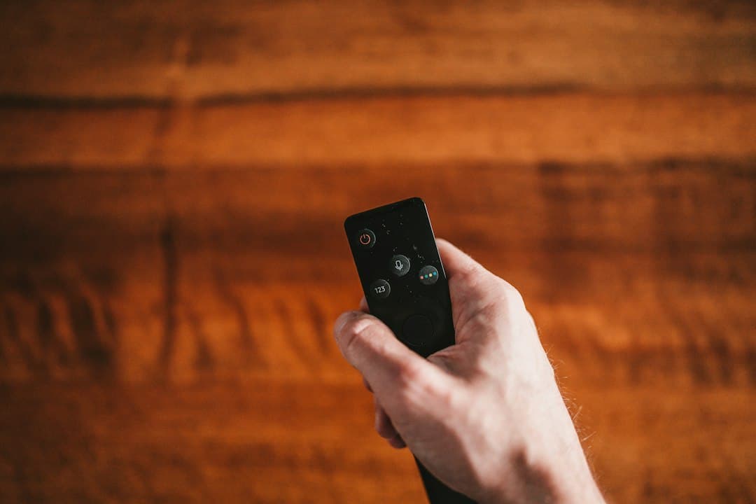 Hånd der holder en fjernbetjening – vælg det rigtige IPTV-abonnement